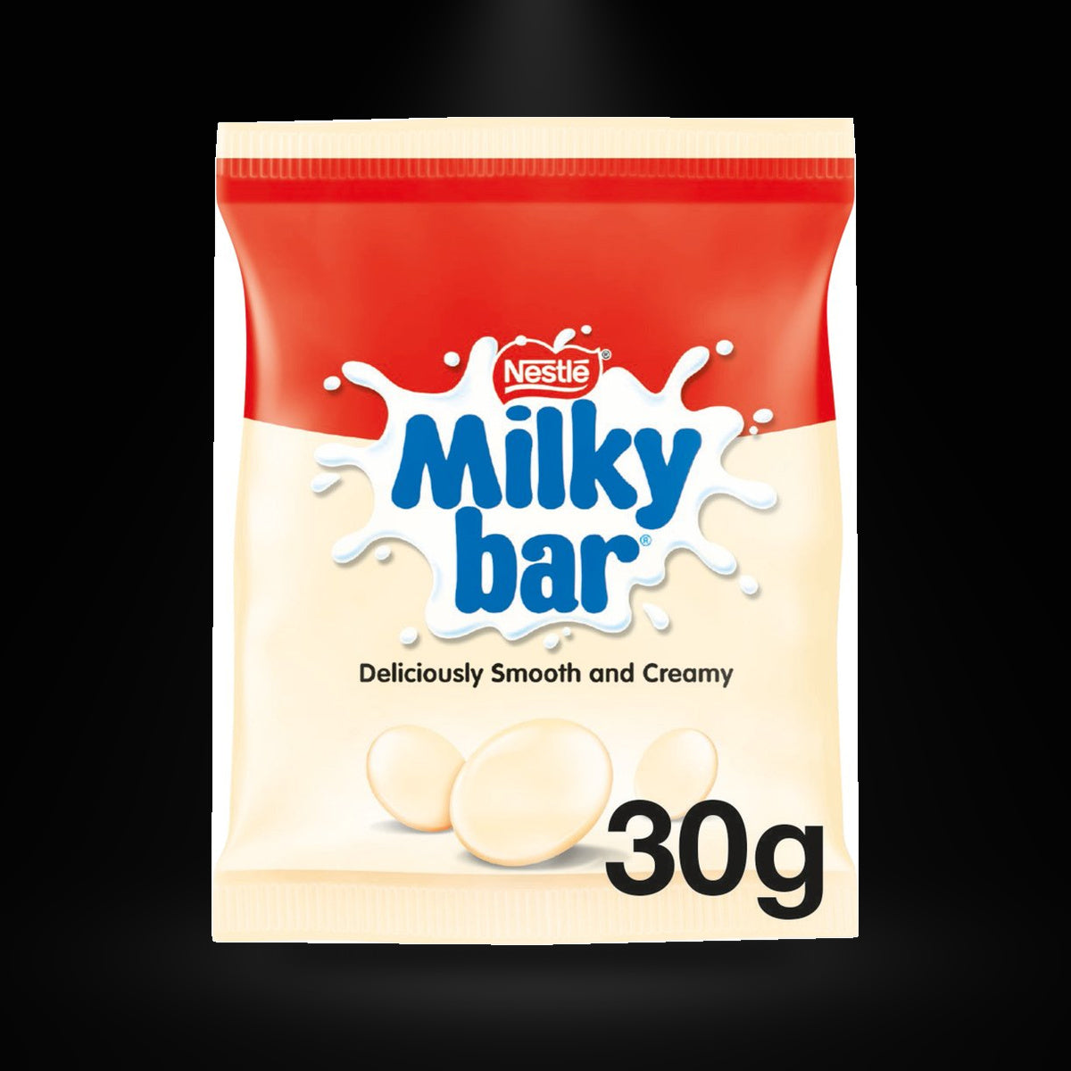 Milkybar pieces 30g on a black background with an overhead spotlight