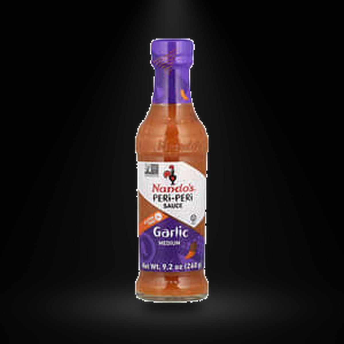 Nando's Garlic Medium Peri-Peri Sauce 260G on a black background with an overhead spotlight