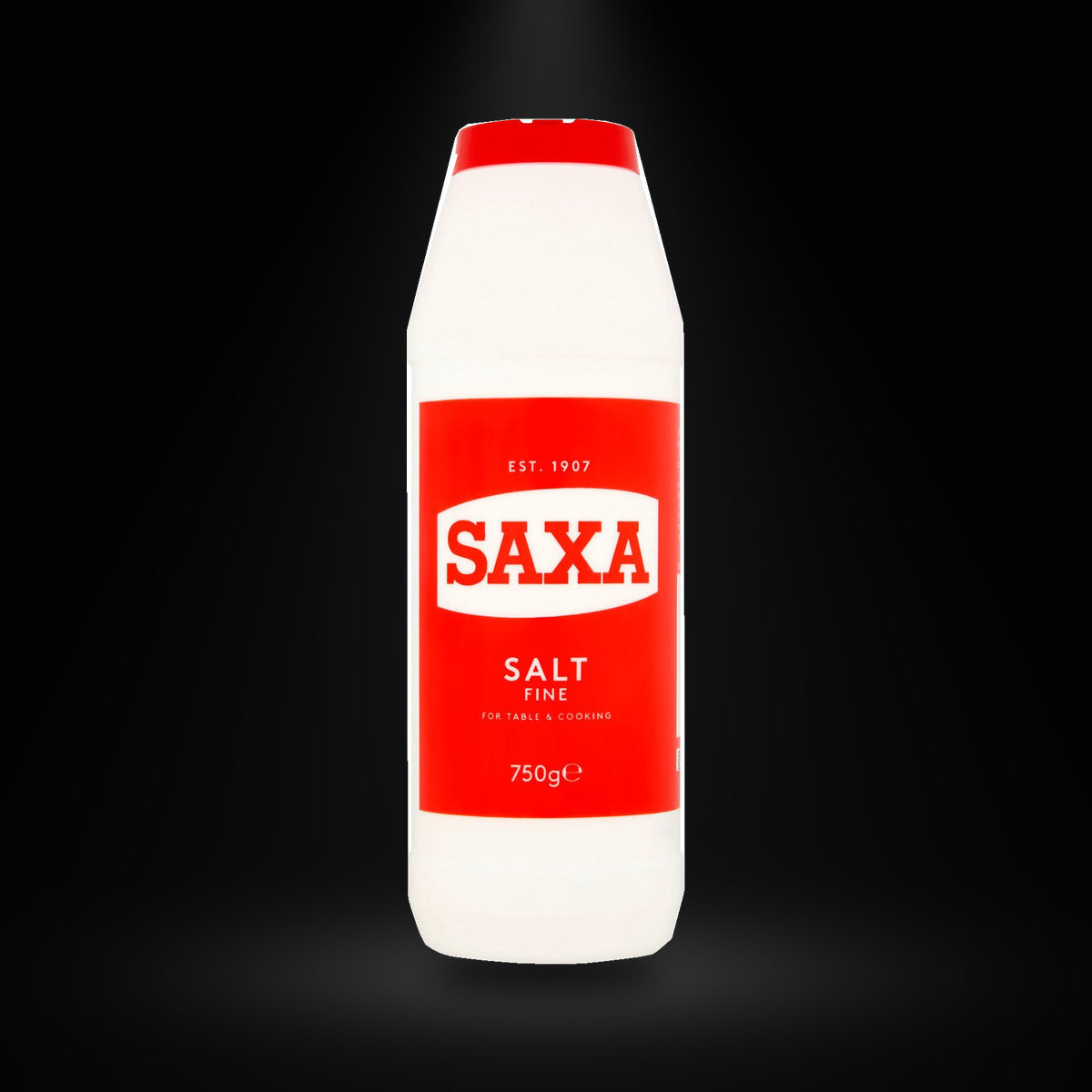 Saxa Salt 750G on a black background with an overhead spotlight